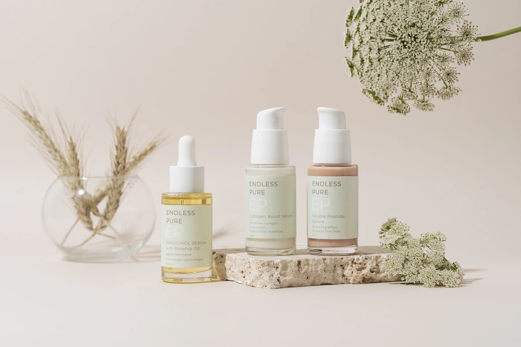 Skincare bottles arranged with delicate flowers on a neutral shelf